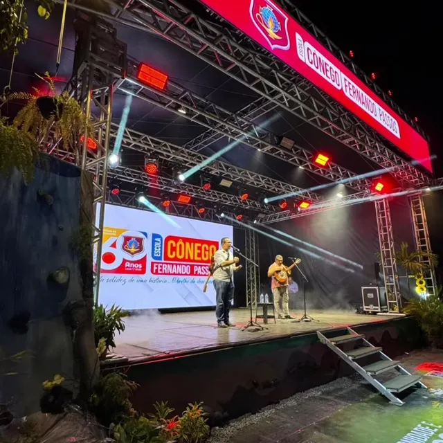 Palco da AACC 2025 iluminado à noite, no pátio da escola