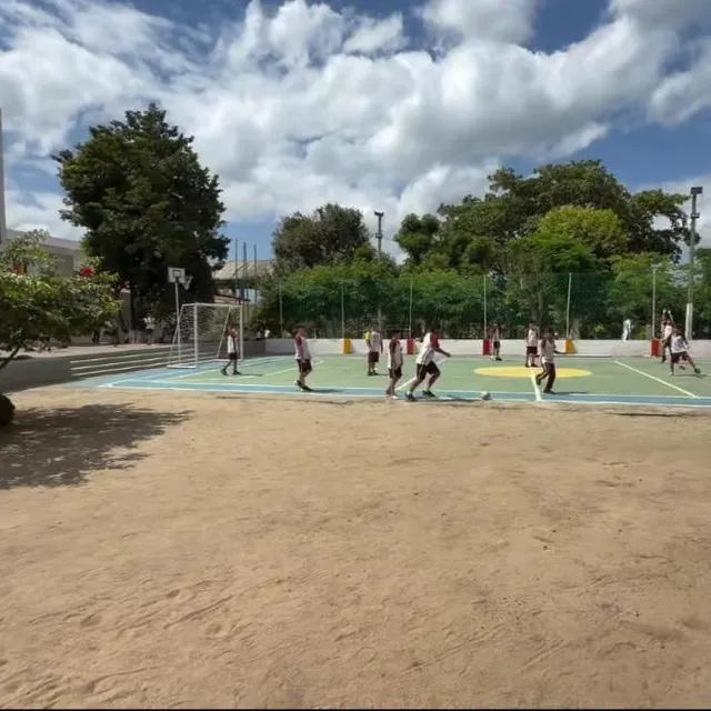Quadra da escola com alunos jogando futebol