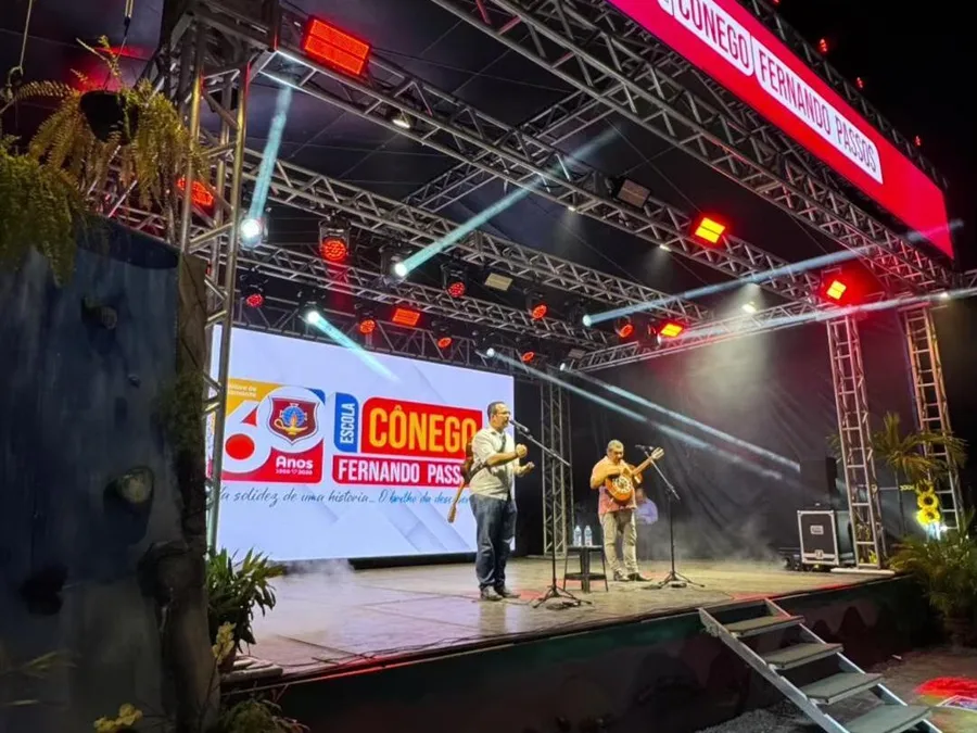 Palco da AACC 2025 montado no pátio da escola, iluminado à noite