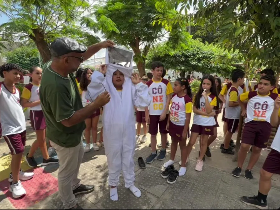 Alunos do Fundamental no pátio conhecendo a roupa de apicultor, no projeto sobre abelhas